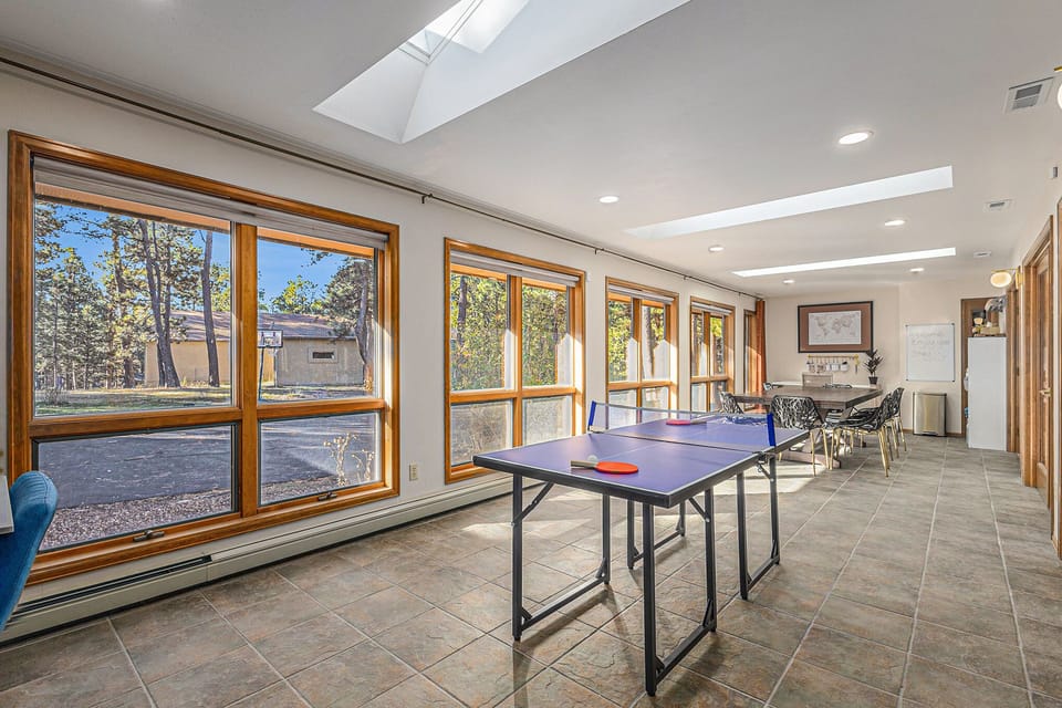 Enjoy sun‑soaked fun in this bright game room, where ping pong, board games, and forest views set the stage for friendly competition, laughter, and relaxed moments together throughout your stay.