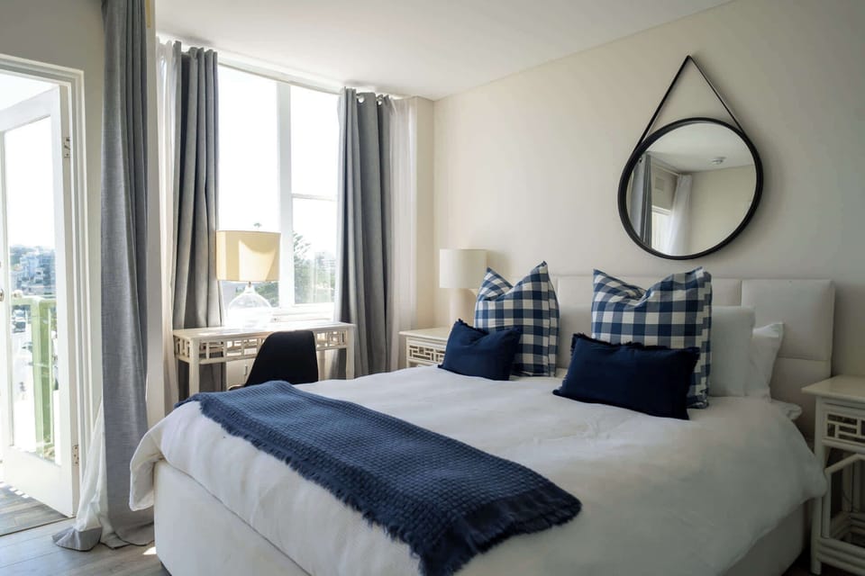 Sunlit queen bedroom with a peaceful outlook and full water views across Manly Harbour
