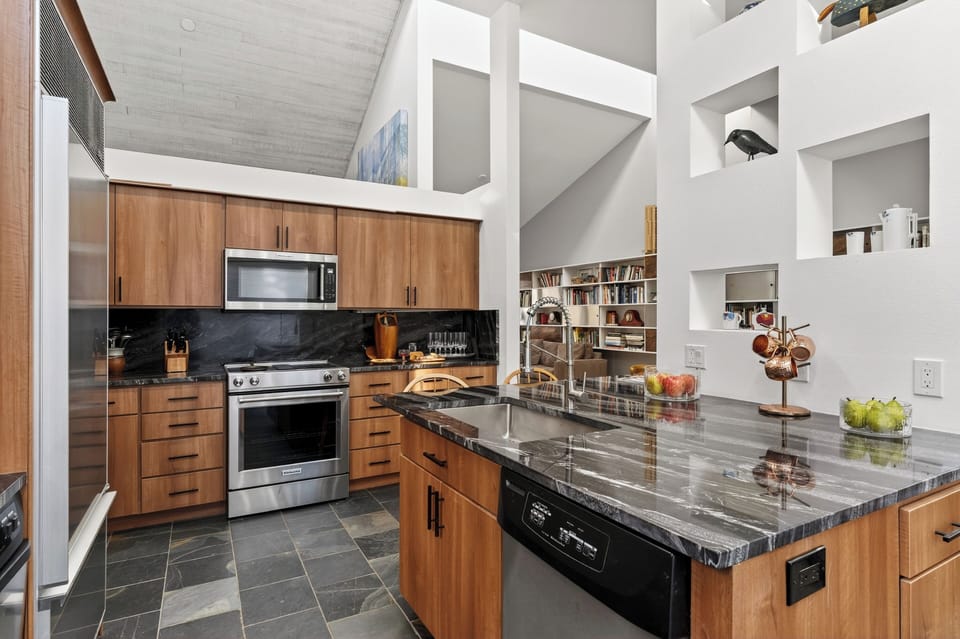 Contemporary kitchen with wood cabinetry, granite countertops, and stainless steel appliances.