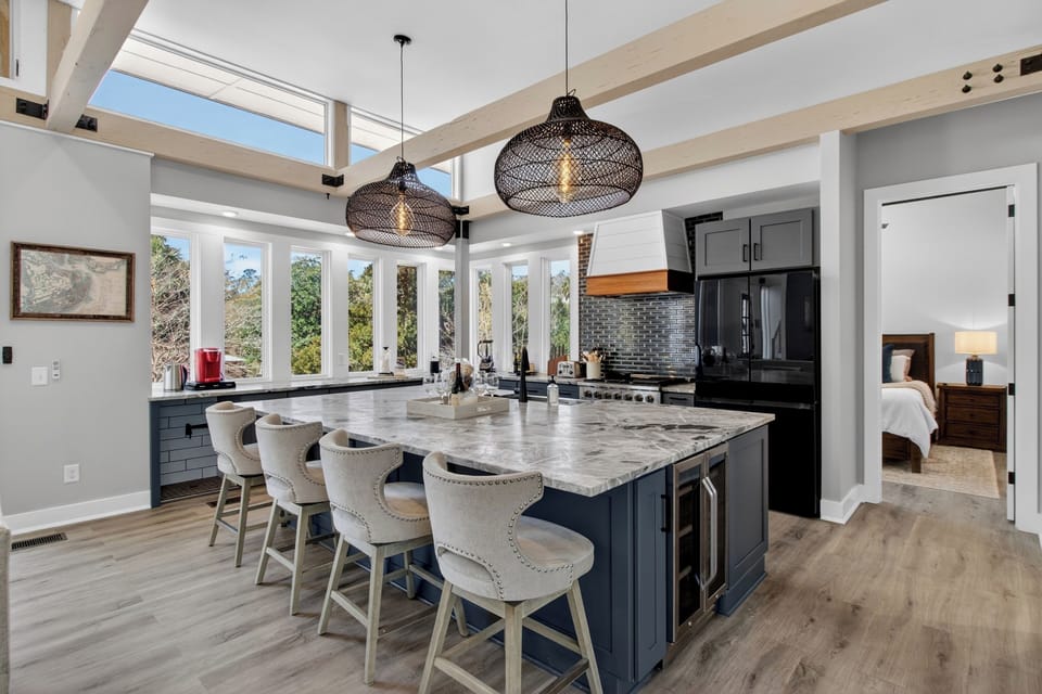 A designer kitchen with a statement island, bar seating, and natural light makes gathering effortless.