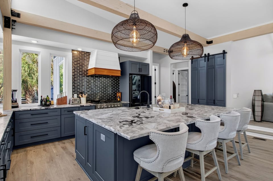 Bright chef’s kitchen with a large marble island and modern blue‑gray cabinetry.