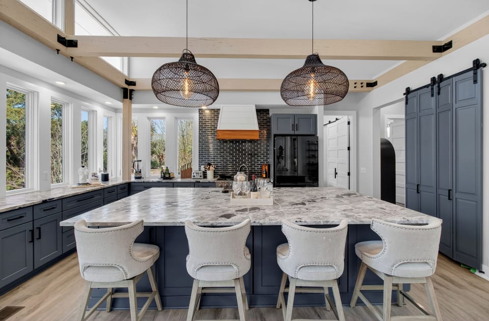 Bright chef’s kitchen with a large marble island and modern blue‑gray cabinetry.