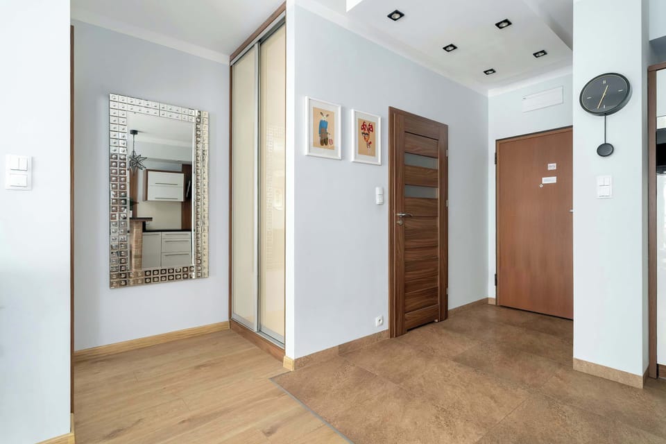A practical entrance hall with a large mirror and a dark wood door leading to the main living area.