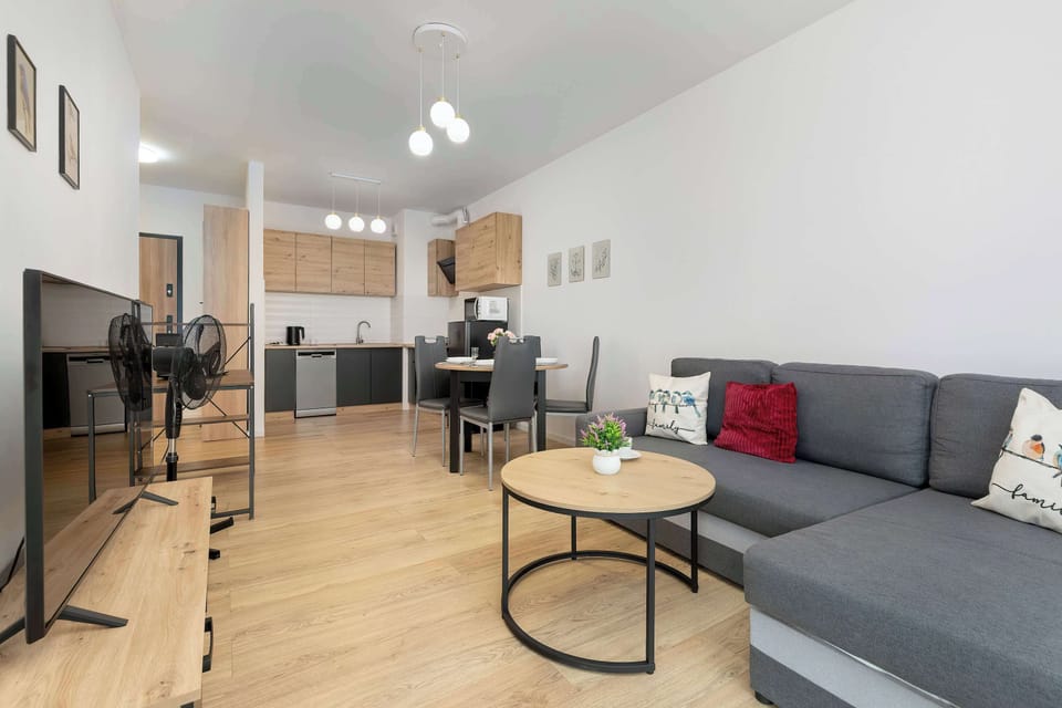 A lounge area with a gray sofa, round coffee table, and open-plan kitchen visible further back.