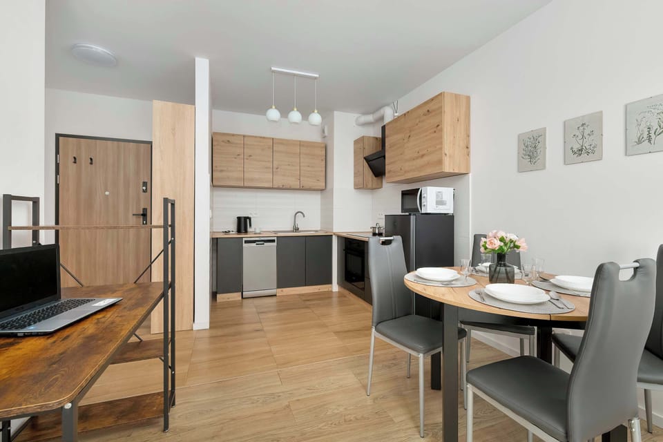 A dining and kitchen area combined, with a wooden dining table, upholstered chairs, and pendant lighting above.