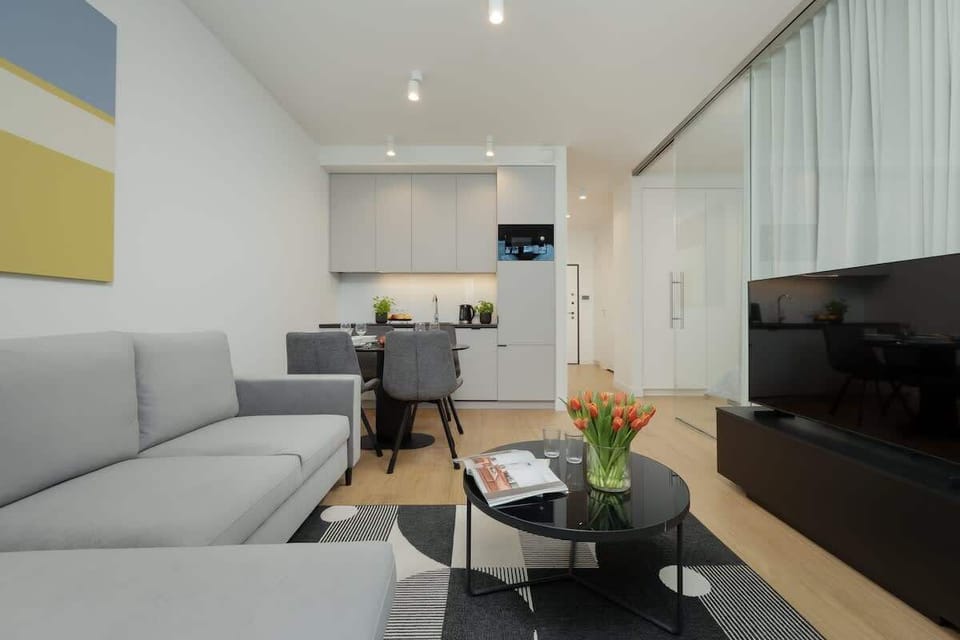 Bright living room with a gray sofa, a round coffee table, and modern wall art.