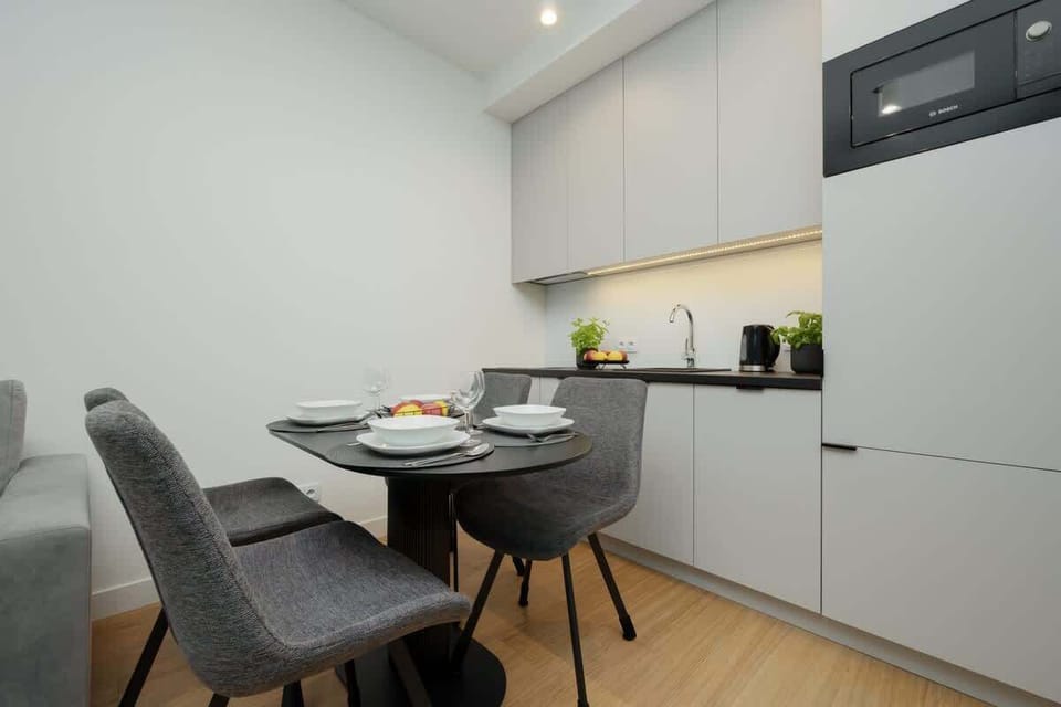 Spacious layout with a dining table, chairs, and a sleek kitchen in the background.