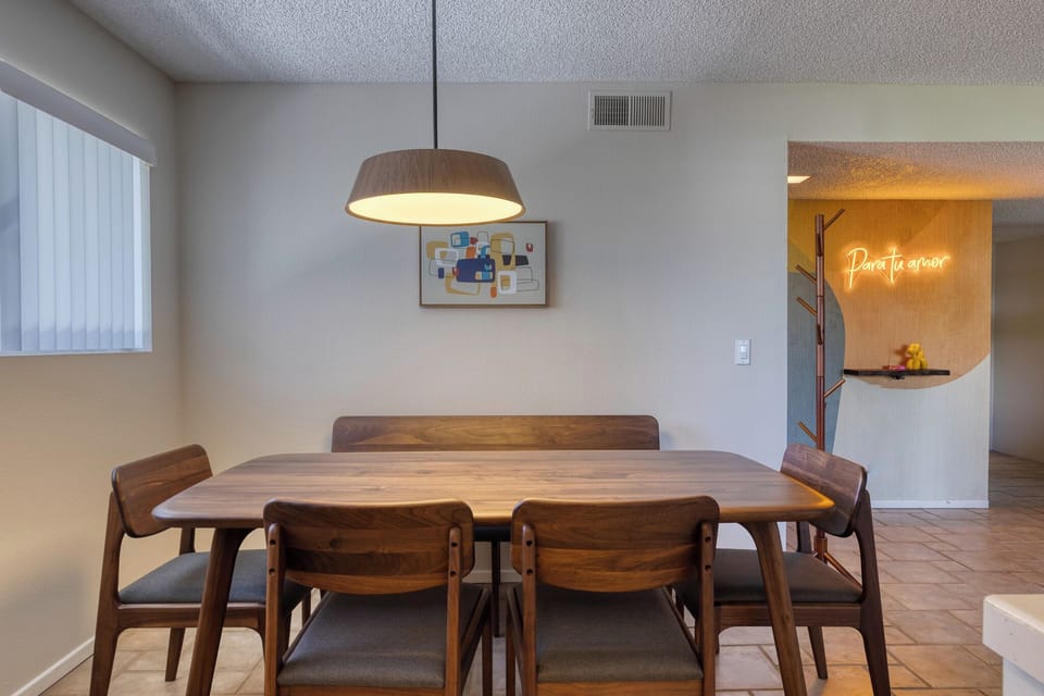 Gather around your elegant walnut dining table for memorable meals beneath warm pendant lighting and modern art.