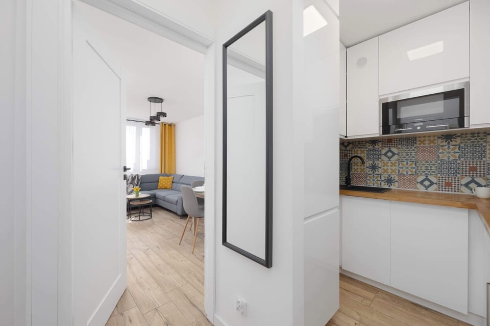 A compact kitchen with modern cabinets and a patterned backsplash. Clean and functional design.
