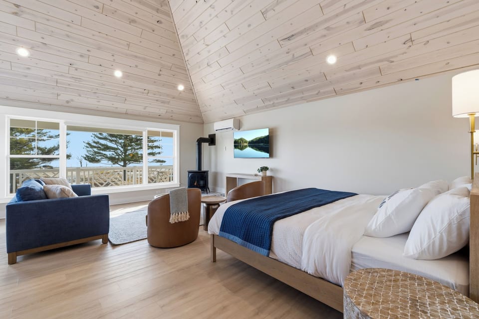 King bed with lake views wood stove and vaulted shiplap ceiling
