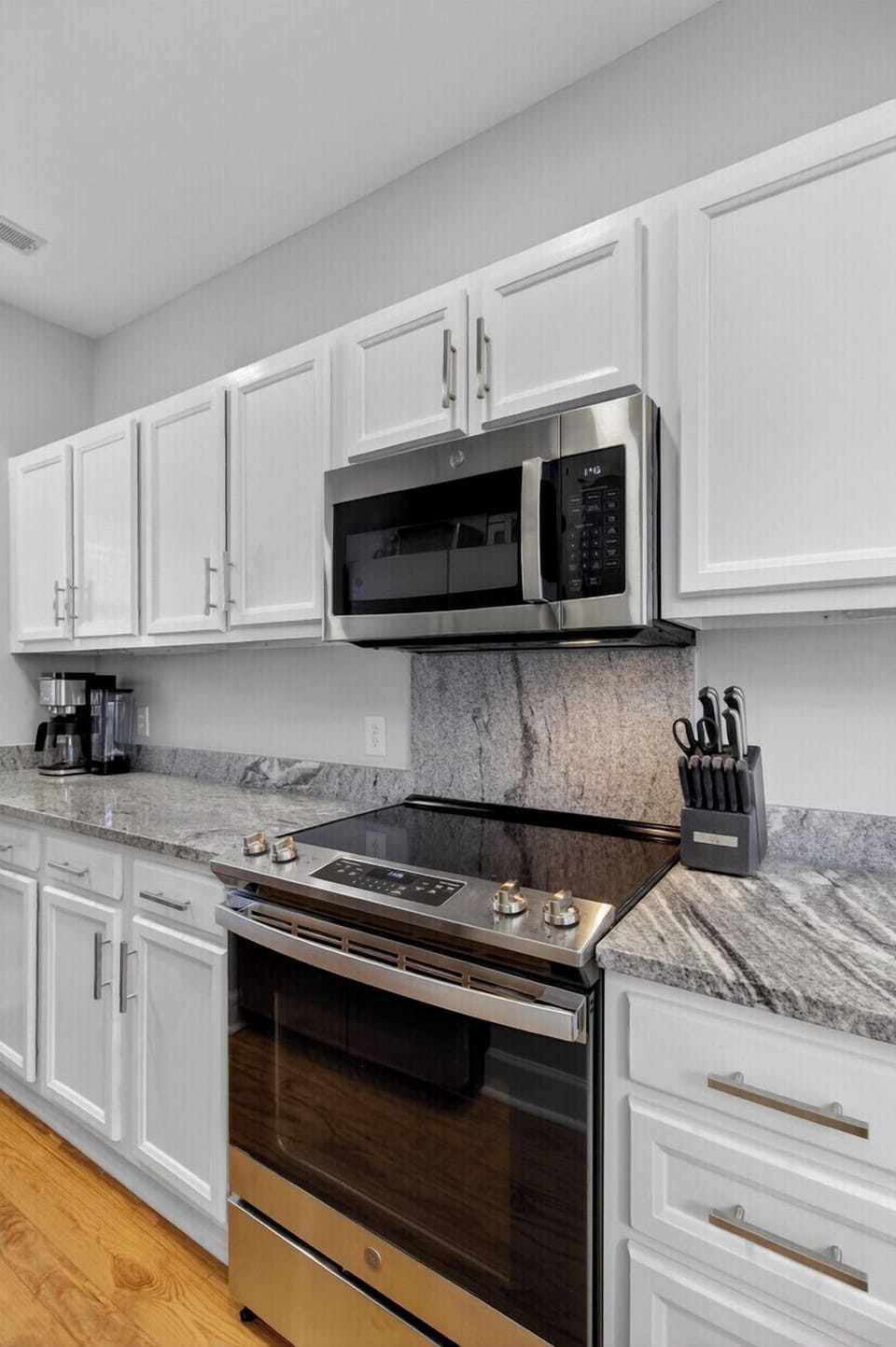 Cook your favorite meals in this sleek kitchen with granite countertops, stainless steel appliances, and crisp white cabinets.