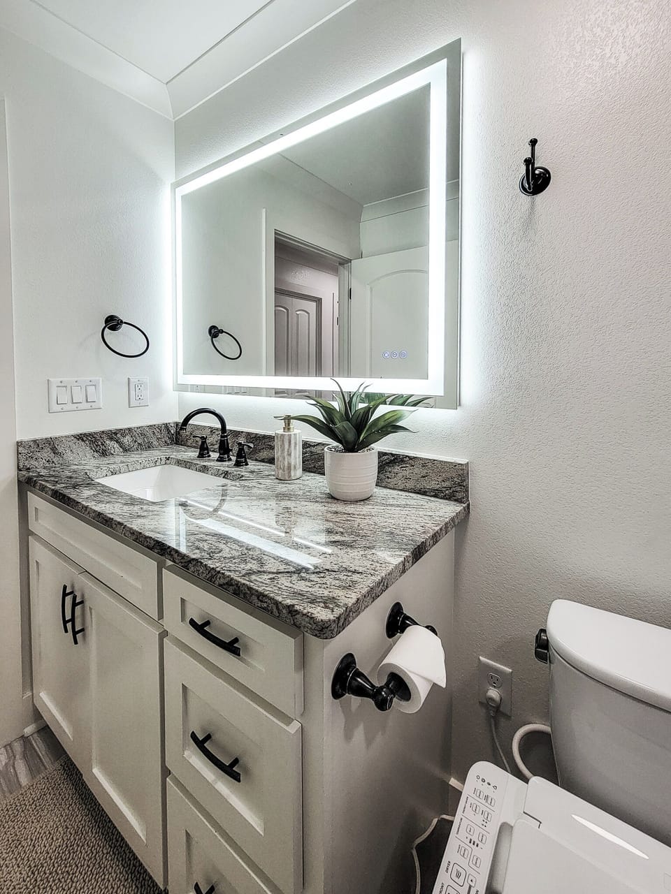Step into your beautifully appointed bathroom featuring a granite vanity, LED-lit mirror, and modern amenities for your comfort.