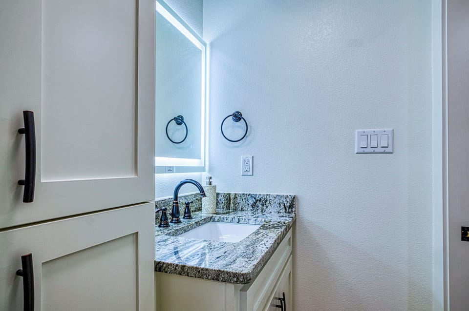 Step into your pristine bathroom featuring elegant granite countertops and bright LED mirror lighting for your morning routine.