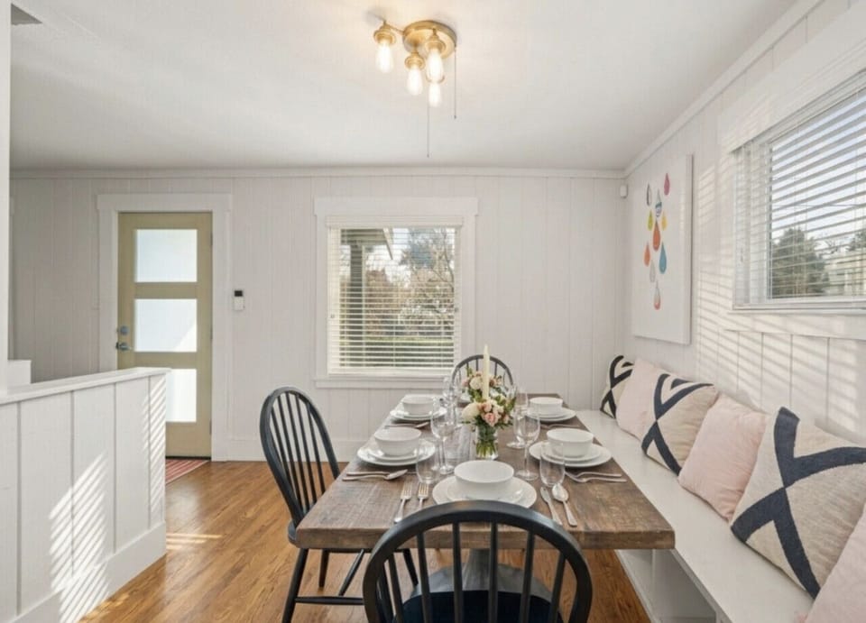 A bright and inviting dining space with a solid wood table, black chairs, and a cozy built-in bench with soft cushions.