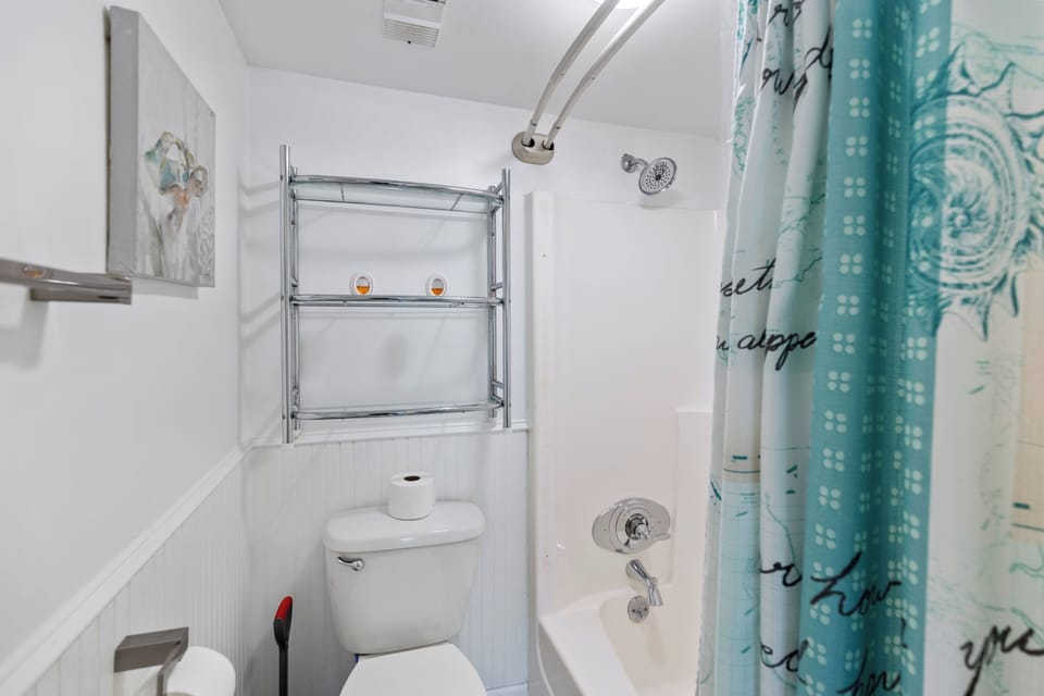 Step into your private bathroom featuring a relaxing tub-shower combo with decorative curtain and convenient storage shelving.