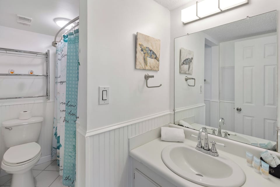 Your bright bathroom features coastal charm with sea turtle artwork and fresh white finishes for a refreshing start to each day.