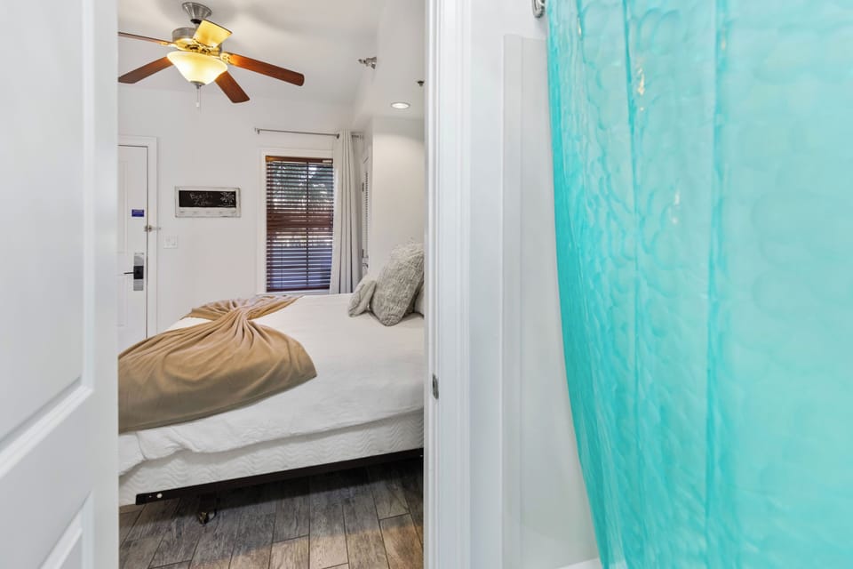 Drift off to peaceful sleep in your cozy bedroom, where a ceiling fan keeps you cool and natural light filters through blinds.