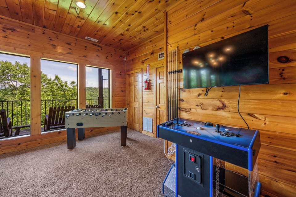 Lazy Bear's game room with large windows offering a scenic mountain views and access to a balcony with rocking chairs