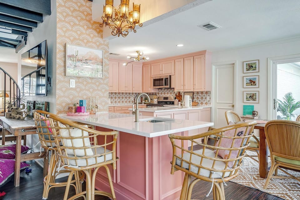 Pink cabinets, quartz island, rattan barstools, and room for the whole group to gather. The kitchen at Texas Two-Step is fully stocked and fully styled.