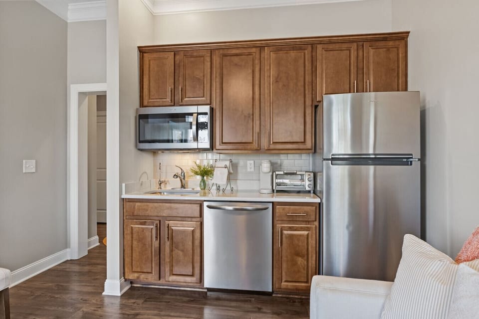 Fully equipped kitchenette with fridge, hot plate, dishwasher, microwave, and ample cabinet space