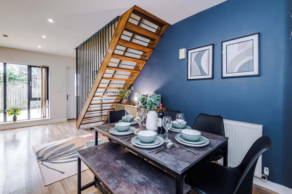 Inviting living room with a versatile sofa bed, sleek coffee table, and warm wood floors. Framed art, greenery, and natural light enhance the cozy ambiance, offering both stylish relaxation and extra sleeping space for guests
