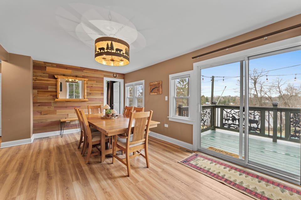 Bright dining room opens to deck with string lights and lake view