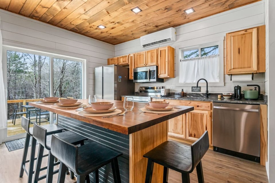 Full kitchen with coffee maker, kettle, toaster, plates, cutlery, and cookware