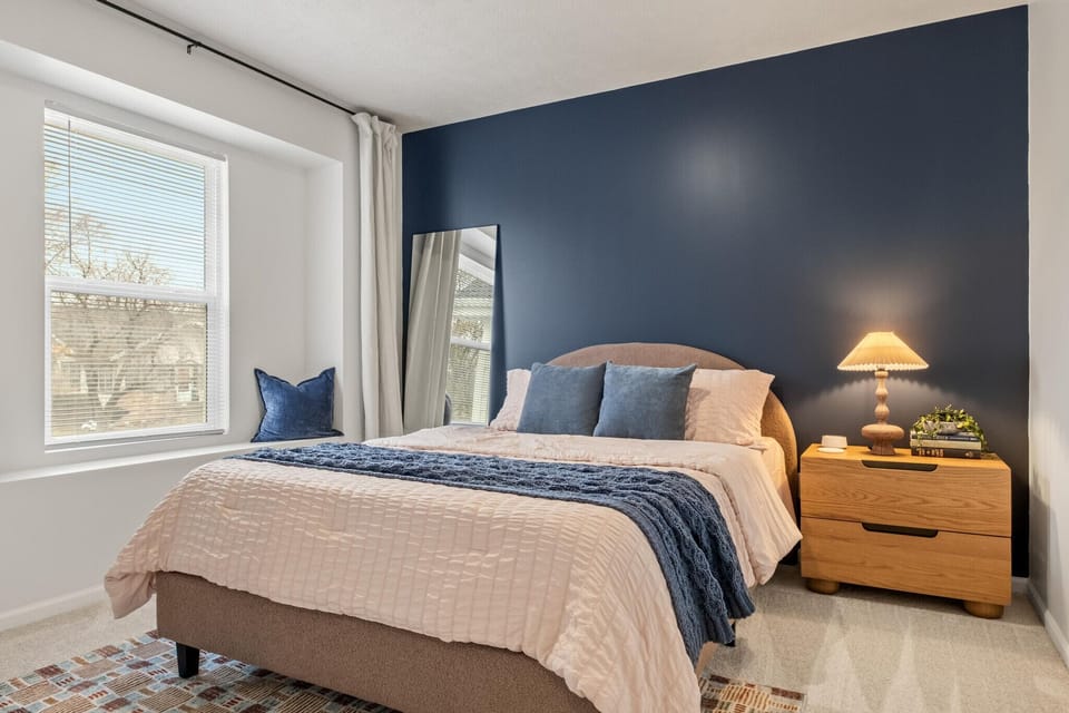 Serene queen bedroom with deep blue accent wall and soft lighting.