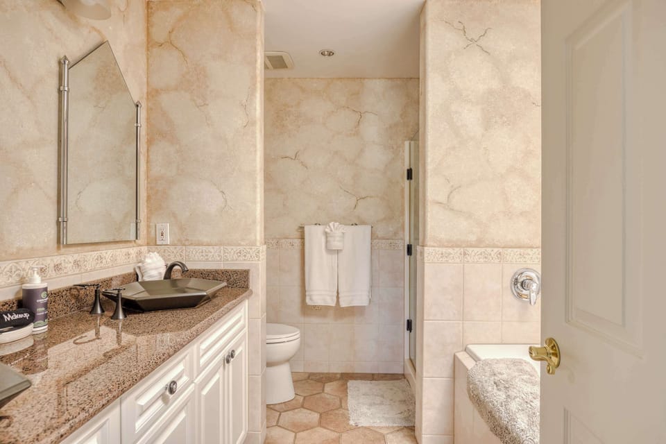 Bright bathroom featuring double sinks, tiled tub and shower, and plenty of counter space for convenience.