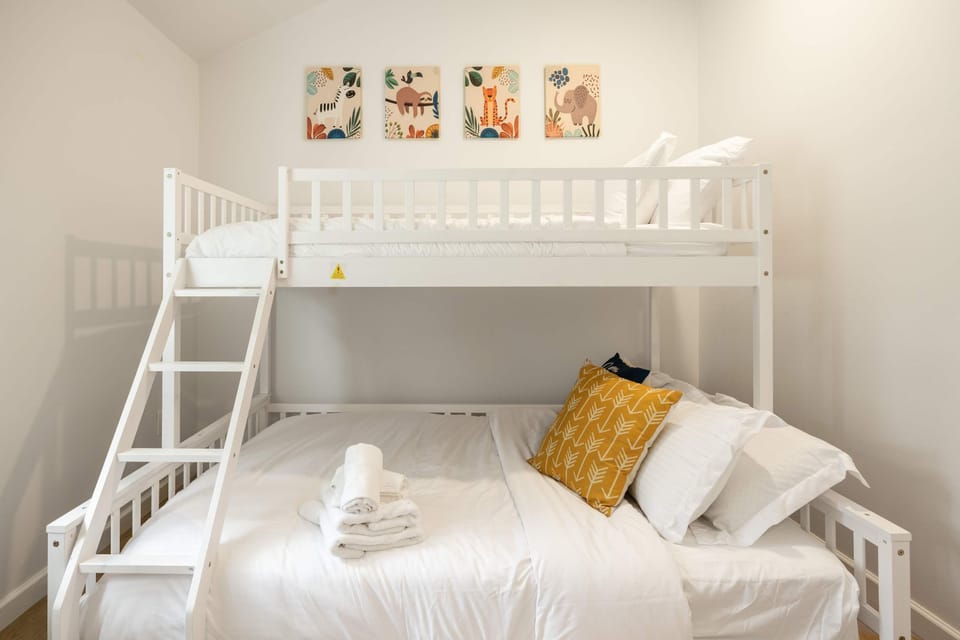 Clean and cozy bunk bedroom with soft linens and charming wall art for a relaxing stay.