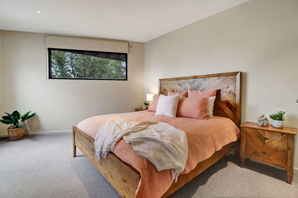 Main Bedroom with Ensuite & WIR - Calm and comfortable main bedroom with timber bed, soft styling and natural light at Banksia House High Country Retreat in Mansfield Victoria.