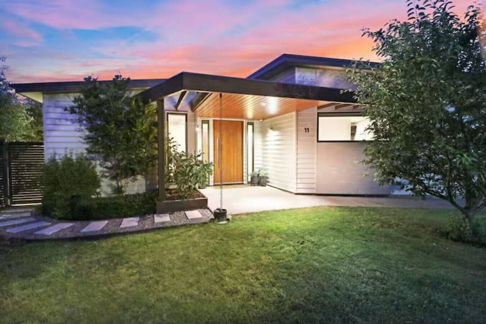 Welcoming front exterior of luxury holiday accommodation with landscaped garden and covered entry at dusk at Banksia House High Country Retreat in Mansfield, Victoria’s High Country.