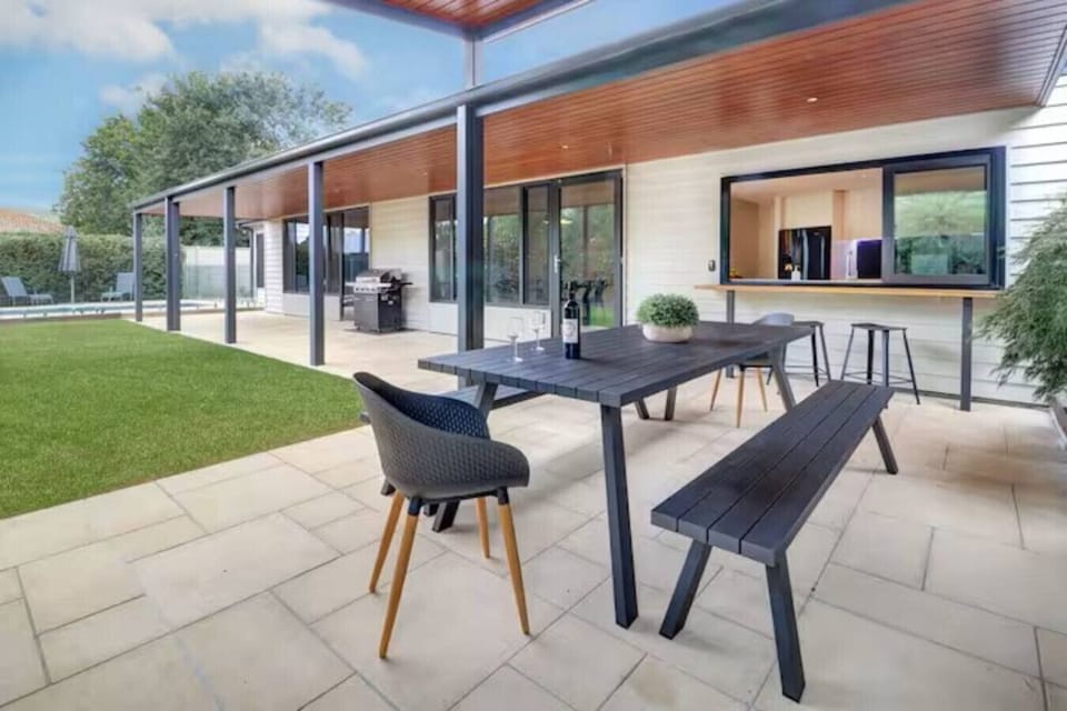 Covered alfresco dining and BBQ area overlooking lawn and pool at Banksia House High Country Retreat holiday accommodation in Mansfield, Victoria’s High Country.