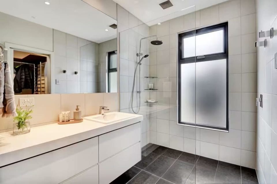 Light-filled private ensuite bathroom with walk-in shower and contemporary finishes connected to the main bedroom at Banksia House High Country Retreat in Mansfield Victoria High Country.