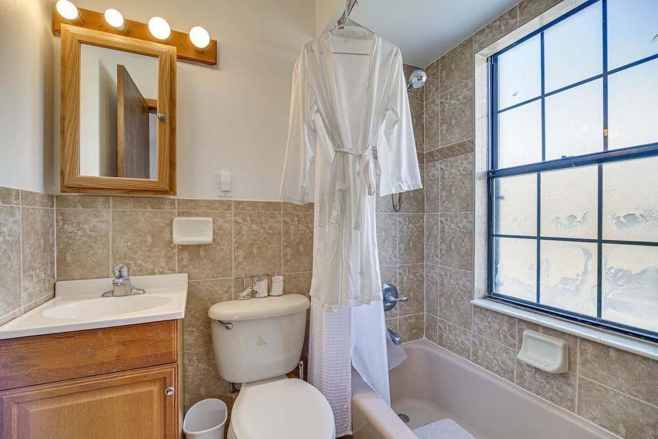 Bathroom with tiled walls, a bathtub, and natural light from a large window.