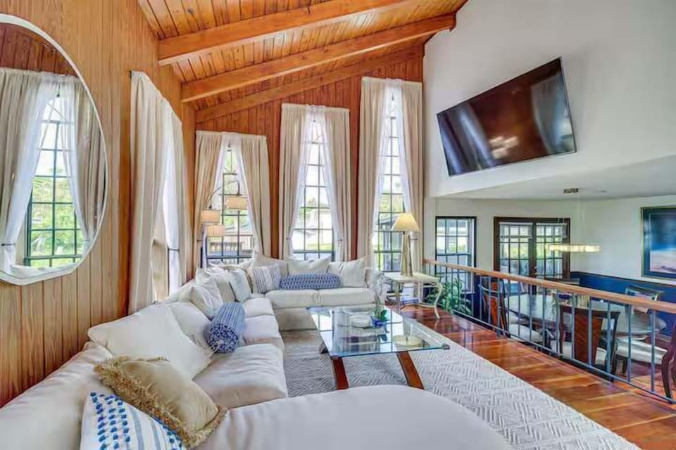 Relax in this spacious living room with vaulted wood ceilings and large windows for natural light.