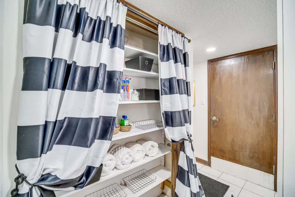 Closet with striped curtains and neatly organized towels and toiletries.