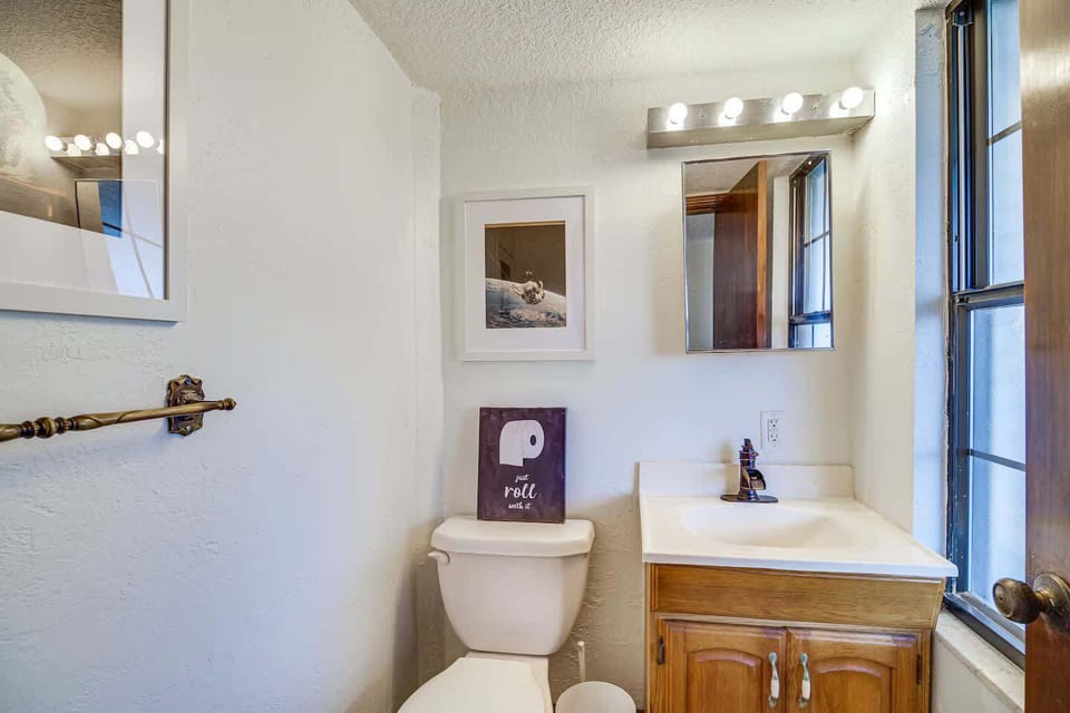 Compact bathroom with natural light and wooden vanity.