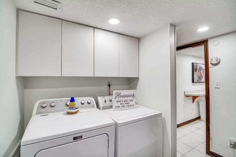 Laundry room with washer, dryer, and overhead storage cabinets.