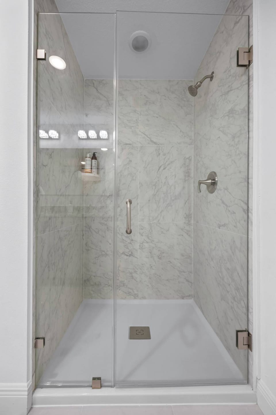Modern shower with glass door and marble-style tile walls