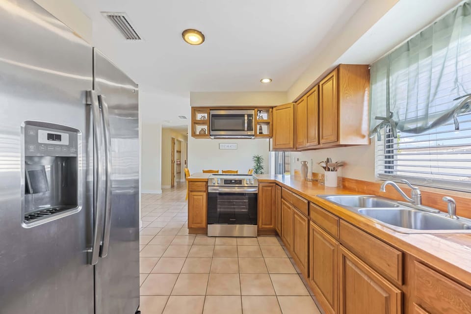 Kitchen with stainless steel appliances and wooden cabinetry overlooking the dining area.