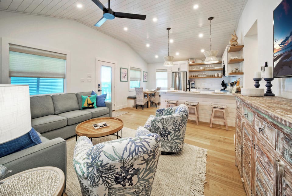 Bright and inviting living area with comfy seating, coastal accents, and a relaxed space to gather. (Boujee Pelican)