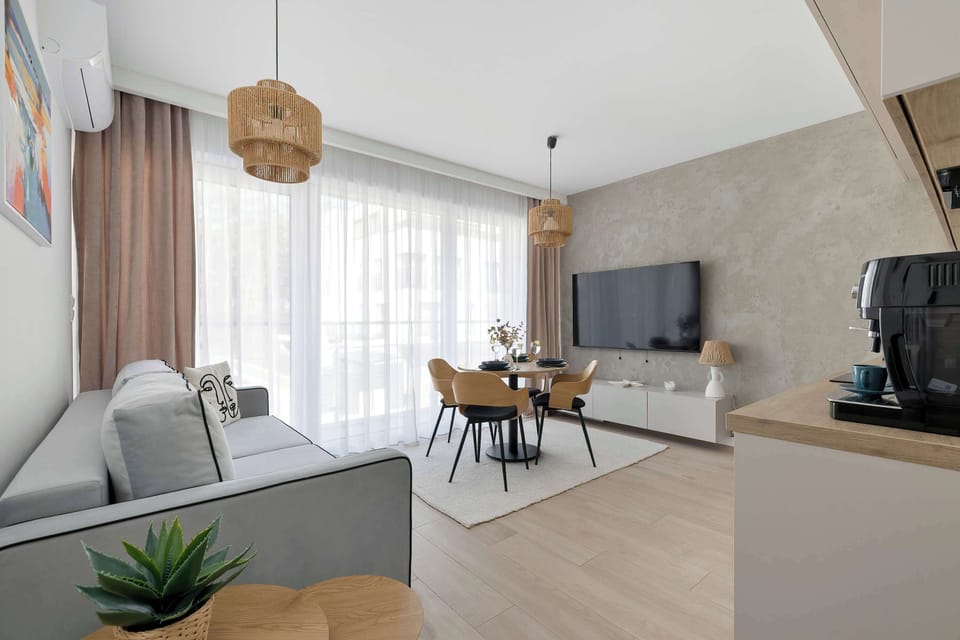 A wide-angle view of the living room highlighting the connection between the seating area, dining space, and the large glass balcony doors.
