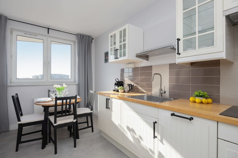 Kitchen and dining perspective shows the seamless connection between the cooking workspace and the small eating area. The light-filled room maintains a clean and streamlined aesthetic.