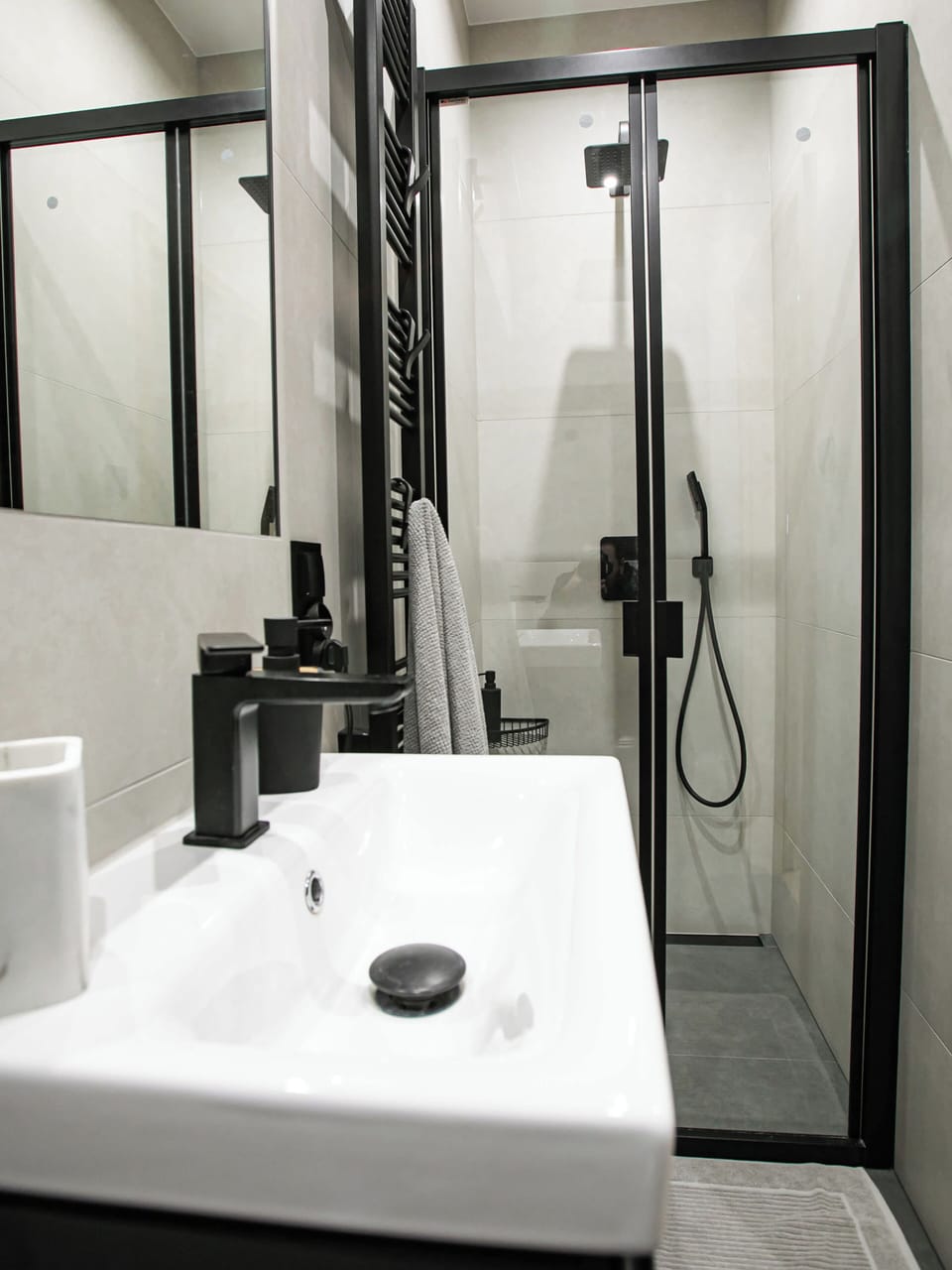 A clear look at the shower cabin with glass doors and chrome fixtures, placed next to a compact sink. The layout maximizes space while maintaining a clean and elegant appearance.