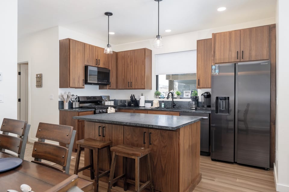 You'll love cooking in this modern kitchen at Base Camp Townhome 106 with sleek wood cabinetry, granite counters, and stainless steel appliances. The island provides extra workspace.