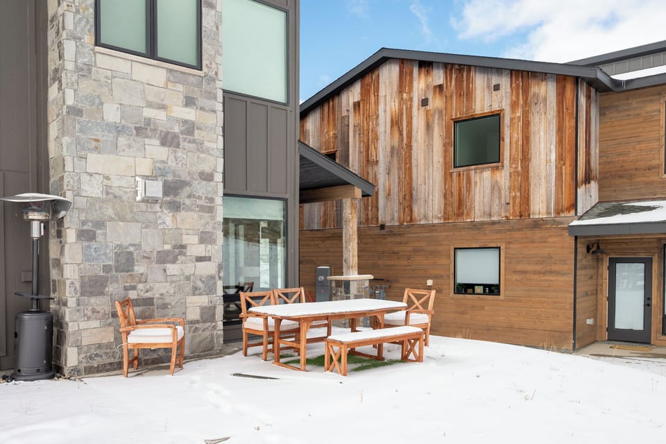 Modern mountain retreat at Base Camp Townhome 106 featuring stone and wood architecture with private outdoor dining space.