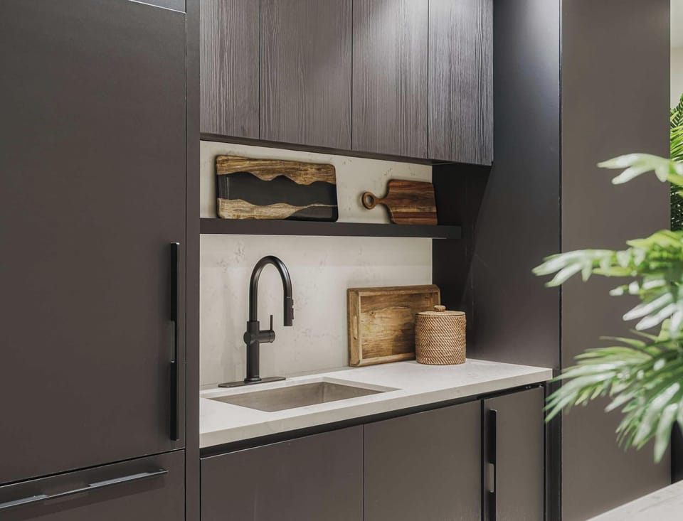 Chic communal kitchenette with modern cabinetry and lush greenery accents
