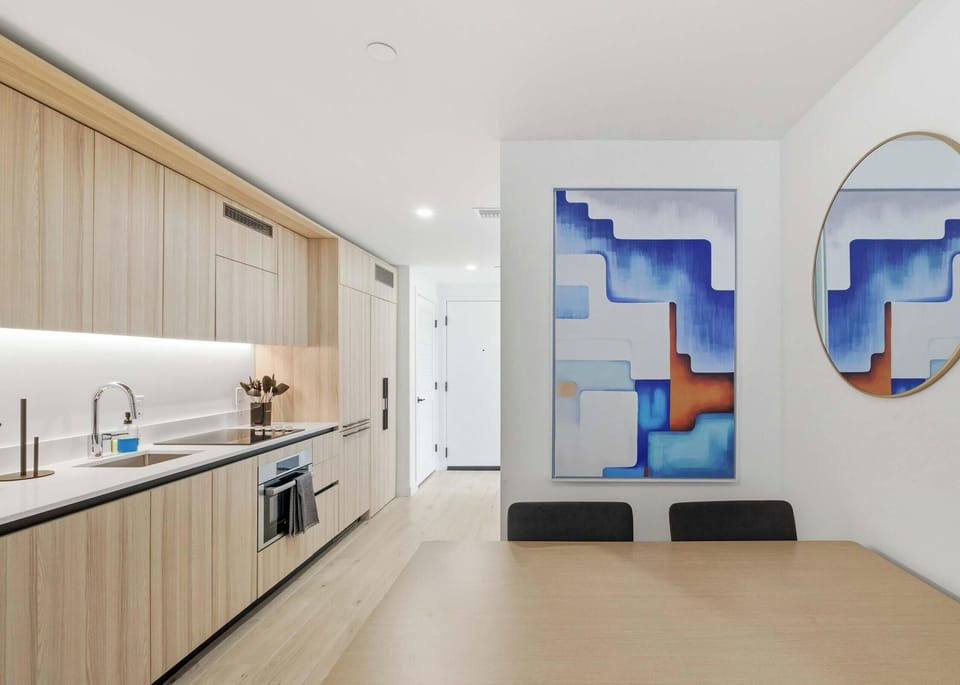Fully equipped kitchen with wood cabinetry, bold art, and modern finishes