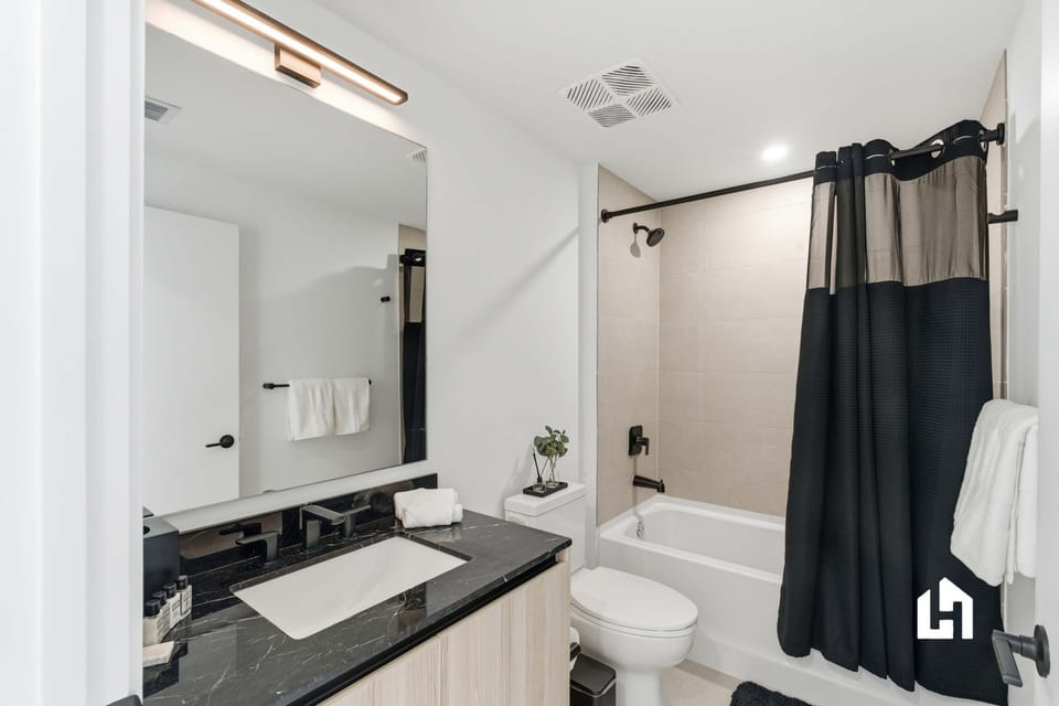 Elegant full bathroom with black marble vanity, shower/tub combo, and modern fixtures

